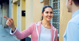 Adult woman standing outdoors giving directions to another person